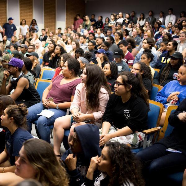 A diverse audience of students filling a large lecture hall